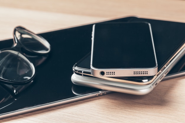 Digital tablet and mobile phone. Electronic devices on wooden table, close up.