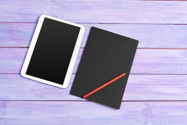 Цифровой планшет и блокнот офис на фиолетовый деревянный