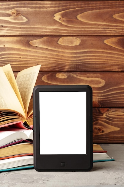 Digital tablet and stack of hardcover books against wooden background