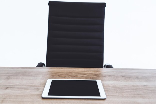 Photo digital tablet on table by empty seat against white background