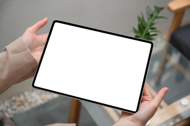흐릿한 최소한의 편안한 생활 공간을 통해 여성의 손에 디지털 태블릿 흰색 화면 모형