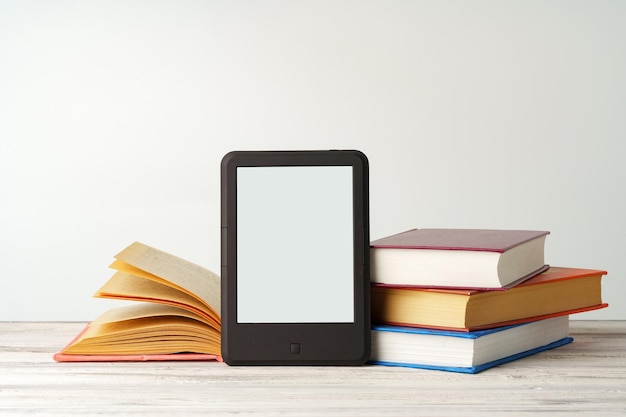 Фото Цифровой планшет со стопкой книг на сером фоне