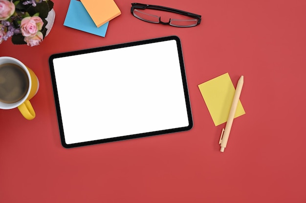 Digital tablet with blank screen colorful sticky notes and coffee cup on red background