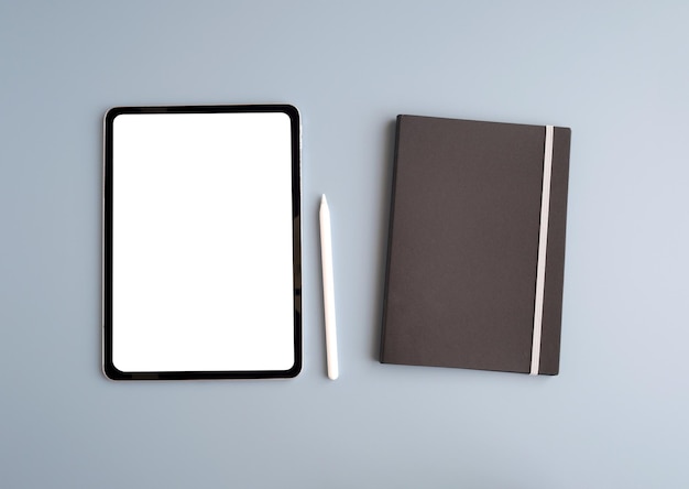 Digital tablet with blank on screen notebook paper and pen isolated on gray background