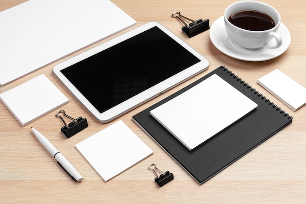 Digital tablet with notepad, supplies and coffee cup on desktop.