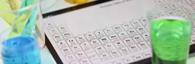 Digital tablet with periodic system of elements lying on table in laboratory closeup checking