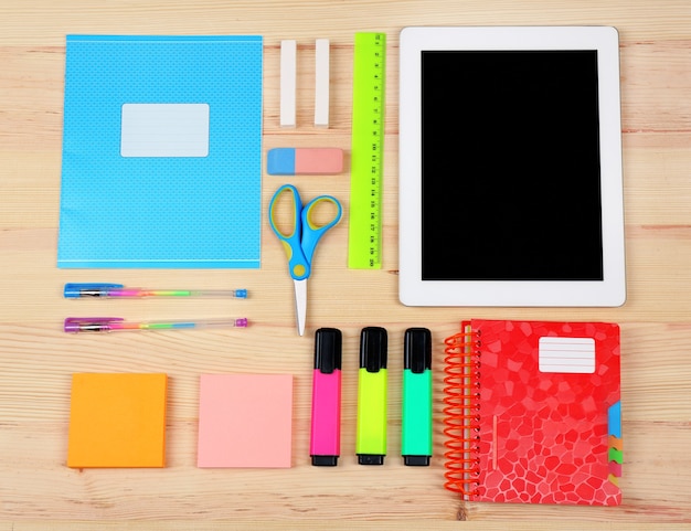 Digital tablet with stationery on wooden table, flat lay