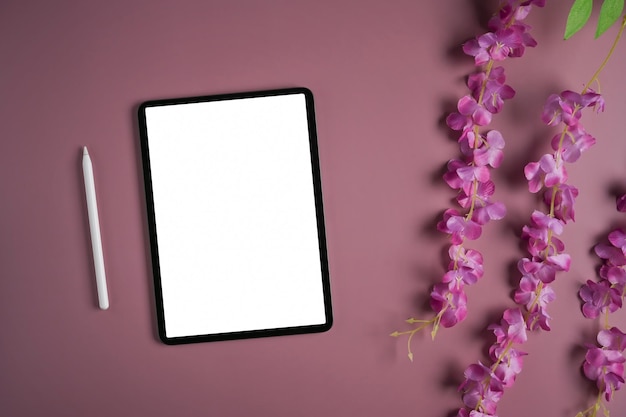 Цифровой планшет с белым стилусом и цветами на фиолетовом фоне