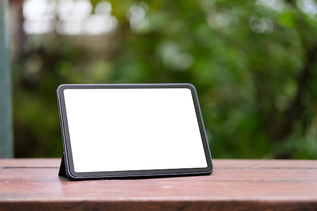 Digital tablet with white screen on wooden table outdoor Blank screen for your advertising text message