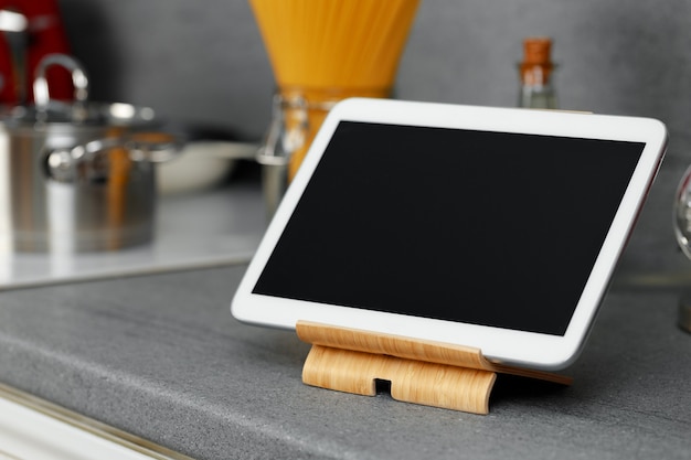 Digital tablet on wooden stand on kitchen counter