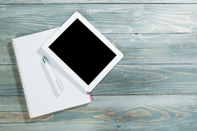 Digital tablet on wooden tablets with notepad and pen