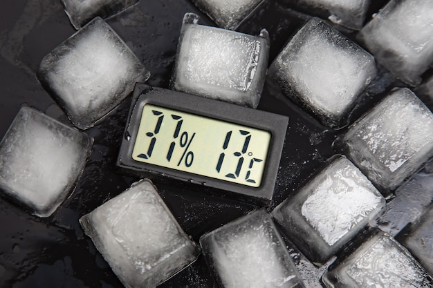 Digital thermometer for measuring air temperature and humidity against the background of frozen ice