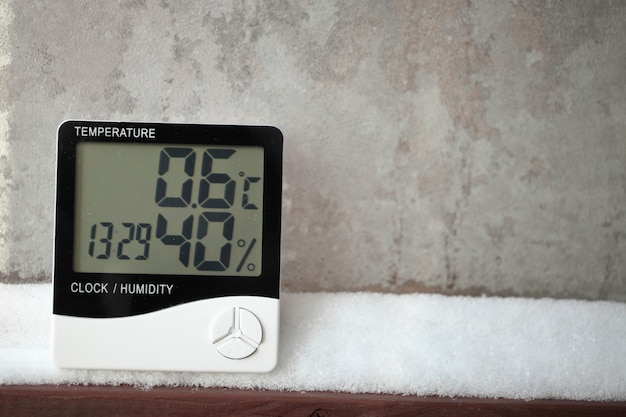 Digital thermometer on a window with snow. Electronic thermometer and hygrometer for temperature and humidity control