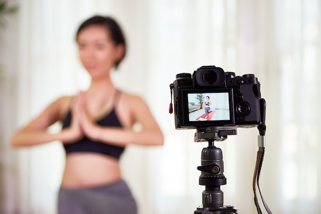 Digitale camera filmt fit jonge vrouw die thuis yoga beoefent, selectieve focus