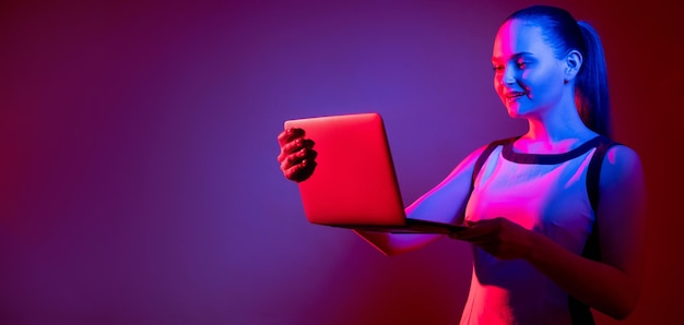 Digitale communicatie Neon banner Moderne technologie Virtuele zaken Slimme vrouw die laptop gebruikt voor videogesprek in roze blauw fluorescerend licht geïsoleerd op paarse kopie ruimte
