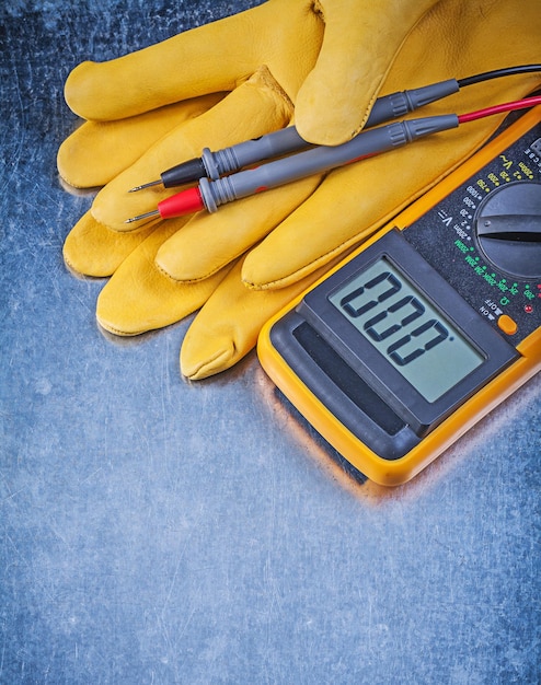 Digitale elektrische tester veiligheidshandschoenen op metalen achtergrond