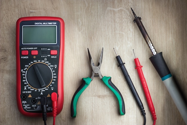 Digitale multimeter, tang en soldeerbout op houten ondergrond. detailopname.