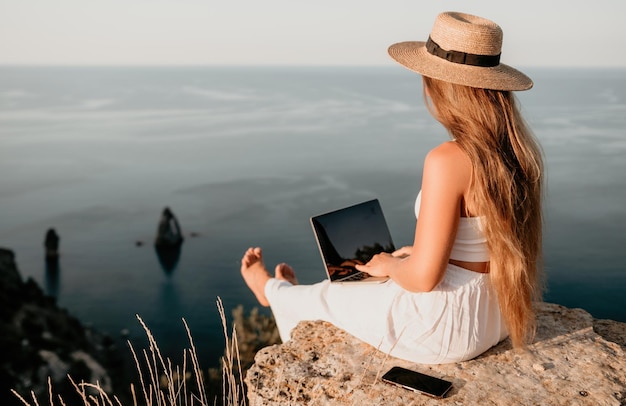 Foto digitale nomade zakenvrouw die op laptop aan zee werkt mooie dame aan het typen op computer aan zee