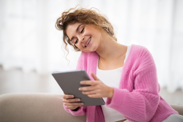 Digitale rust vrolijke jonge vrouw die digitale tablet thuis gebruikt