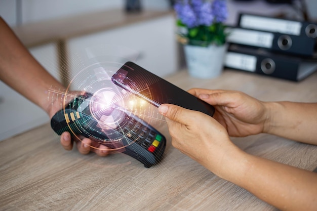 Foto digitale samengestelde afbeelding van een gekapte hand met een smartphone en een creditcardlezer op tafel