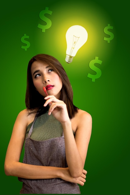 Foto digitale samengestelde afbeelding van een zakenvrouw die naar een gloeilamp wijst met een dollarteken op een groene achtergrond