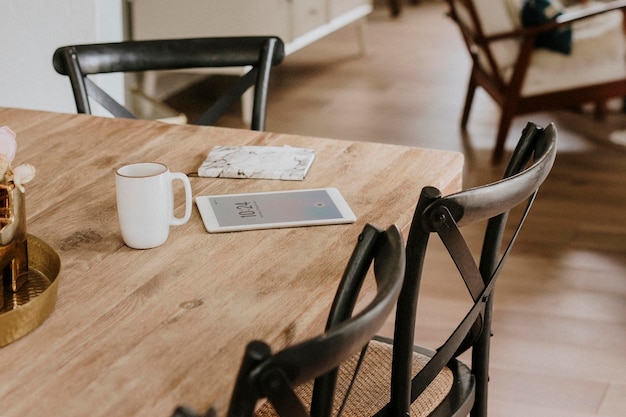 Digitale tablet en een notitieboekje met marmerstructuur op een houten eettafel