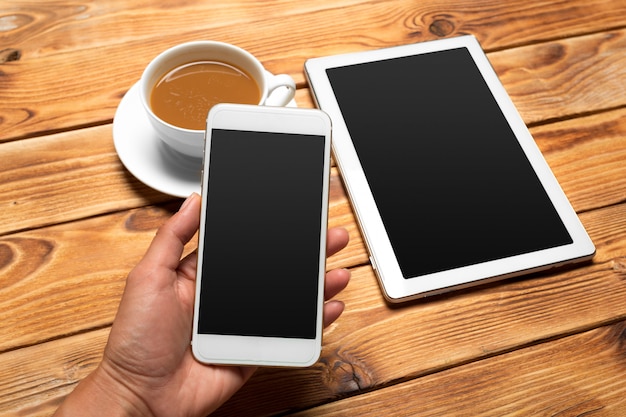 Digitale tablet en koffiekopje op houten tafel