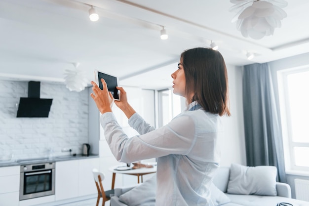 Digitale tablet in handen Jonge vrouw is overdag binnenshuis in slimme huiskamer