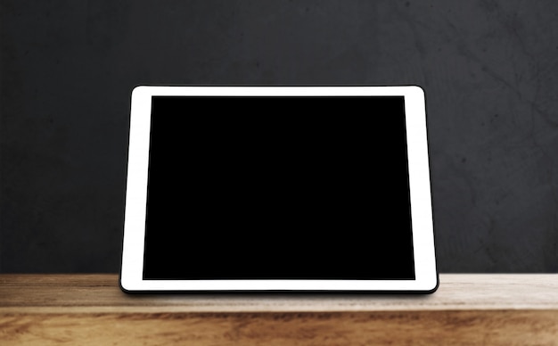 Digitale tablet op houten tafel met zwarte muur
