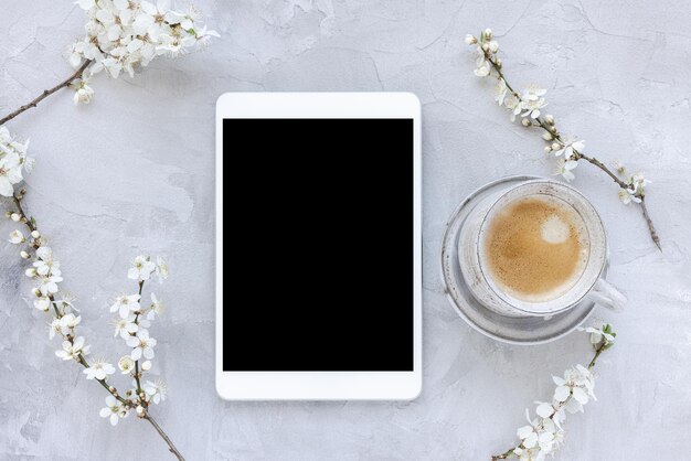 Digitale tablet op lente bloemen witte kersenbloesem bloemen als achtergrond en espressokoffie in de ochtend