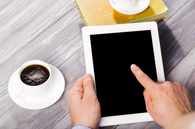 Digitale tabletcomputer met geïsoleerd scherm in mannelijke handen over caféachtergrond - tafel,