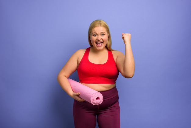 Dik meisje doet sportschool thuis tevreden en met succes expressie paarse achtergrond