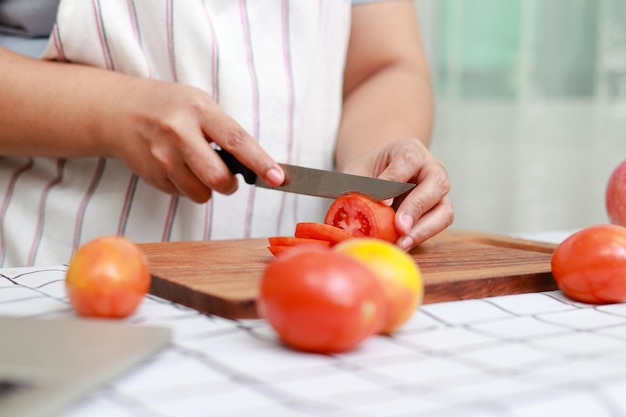 Dikke Aziatische vrouw kookt in de keuken en hakt verse biologische groenten op snijplank Leer salades en gezond eten te maken van het sociale media-gezondheidszorgconcept