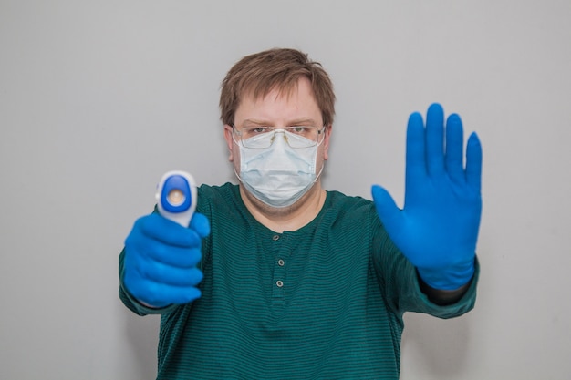 Foto dikke man in een masker en handschoenen met een thermometer zegt stop