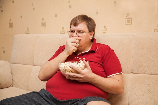 Dikke man tv kijken die popcorn eet