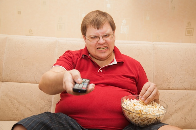 Dikke man tv kijken die popcorn eet