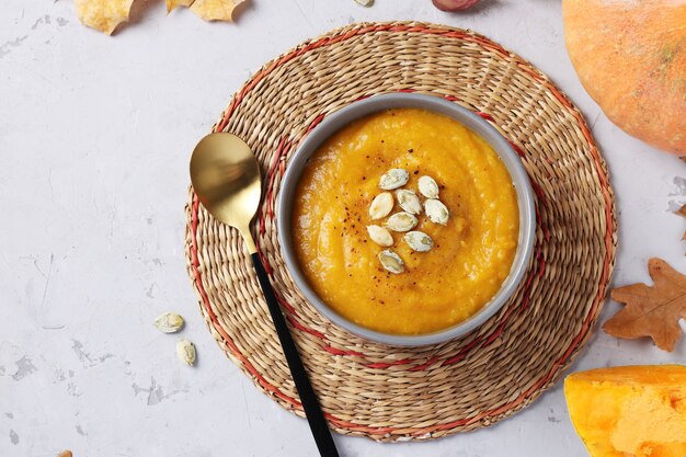 Dikke veganistische herfst romige pompoensoep met zaden in grijze kom. Bovenaanzicht. Ruimte voor tekst