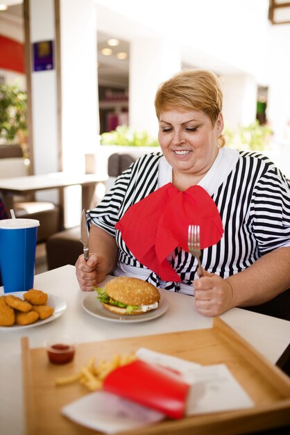 Dikke vrouw bereidt zich voor om fastfood te eten in winkelcentrum food court.