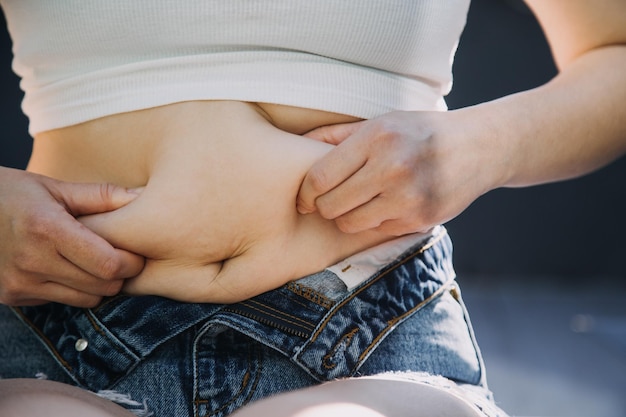 Dikke vrouw dikke buik mollige zwaarlijvige vrouw hand met overmatig buikvet met meetlint vrouw dieet levensstijl concept