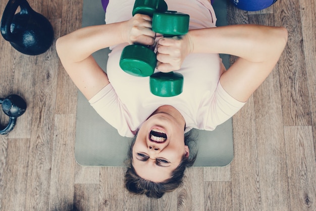 Dikke vrouw doet zeer zware oefeningen in fitnessclub