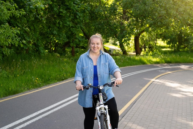 Dikke vrouw fietst in het park, concept van lichaamspositiviteit en gezonde levensstijl