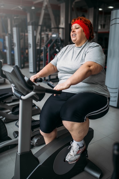 Dikke vrouw training op hometrainer in sportschool