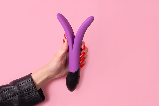 The Dildo in hand on a pink background, sex toy