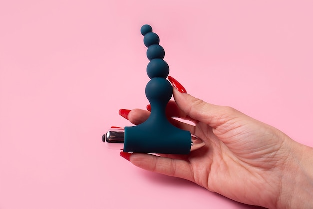 The dildo in hand on a pink background, sex toy