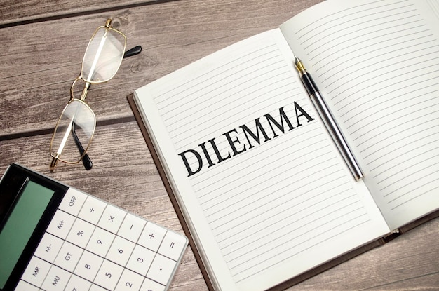 DILEMMA words on brown diary and glasses calculator and pen on wooden desk