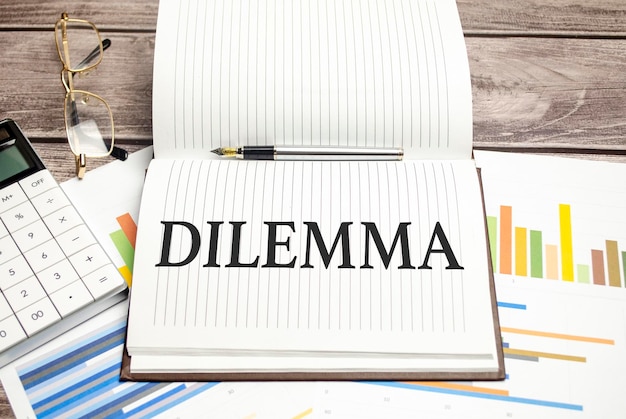 DILEMMA words on brown diary and glasses calculator and pen on wooden desk