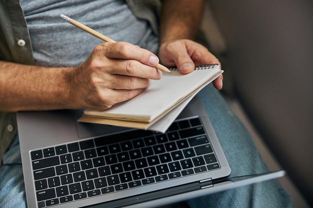 Photo diligent man taking notes while working from home