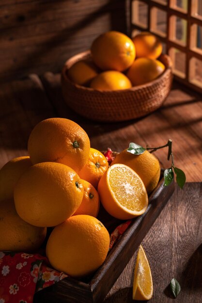 Under the dim light the oranges on the plate are on the wooden table like oil paintings