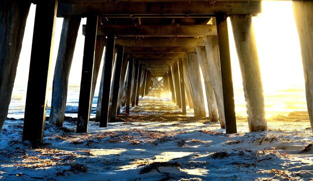 Diminishing perspective of pier at beach during sunset