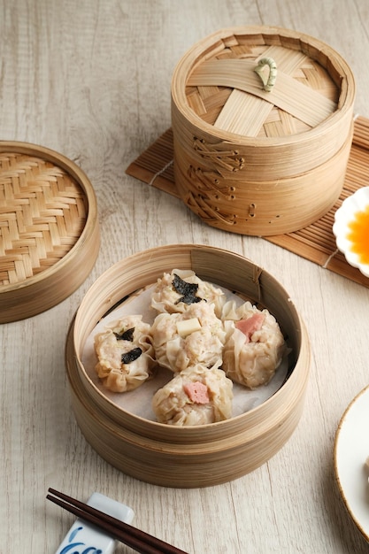 Dimsum met diverse toppings geserveerd in een bamboe steamer en pikante saus Selected focus